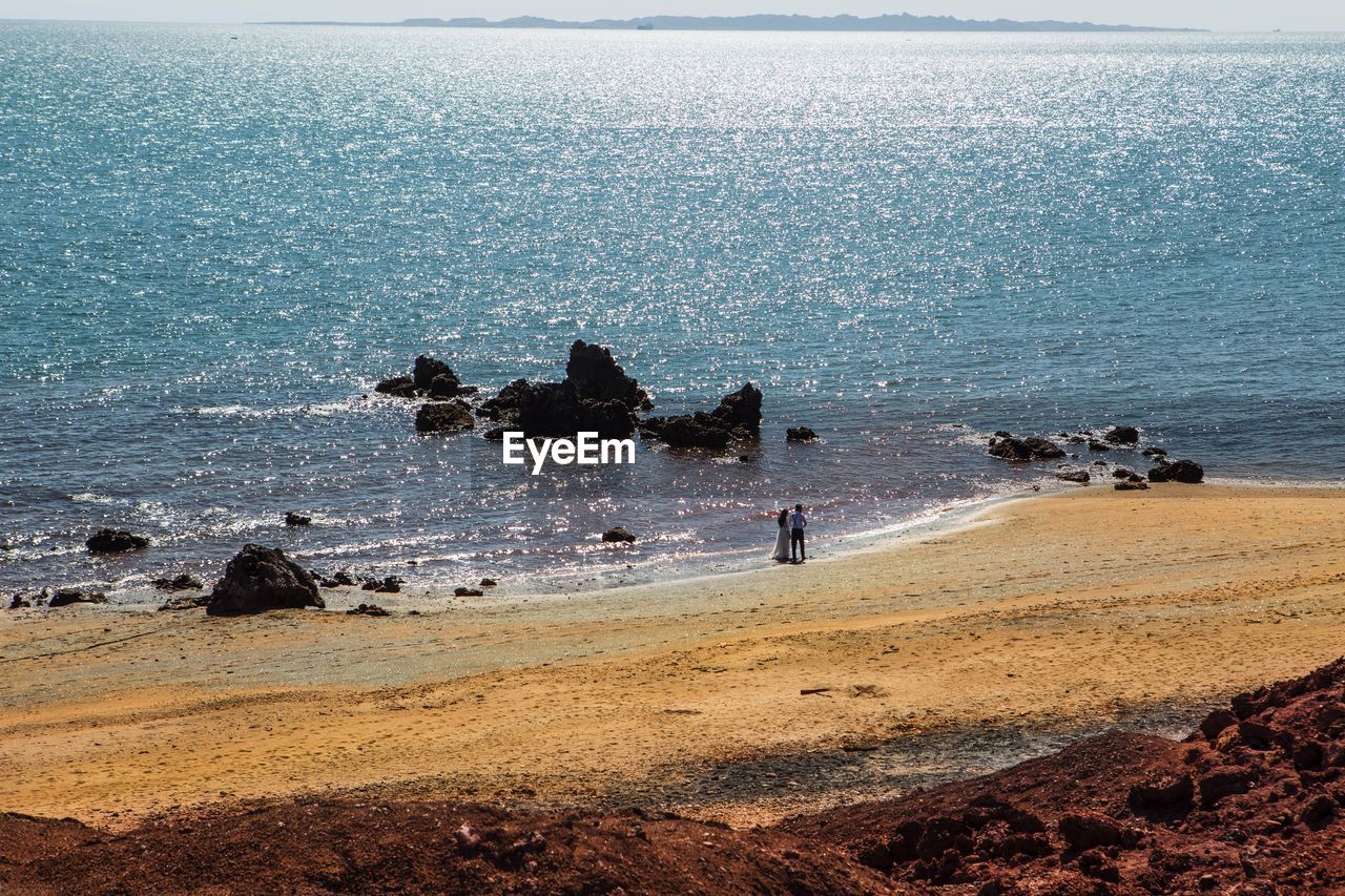 GROUP OF PEOPLE ON ROCK AT BEACH