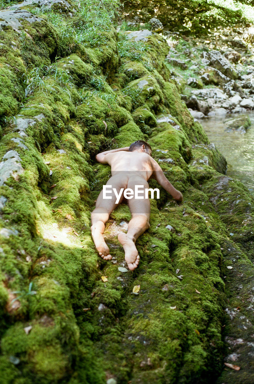 High angle view of naked man lying on rocks outdoors