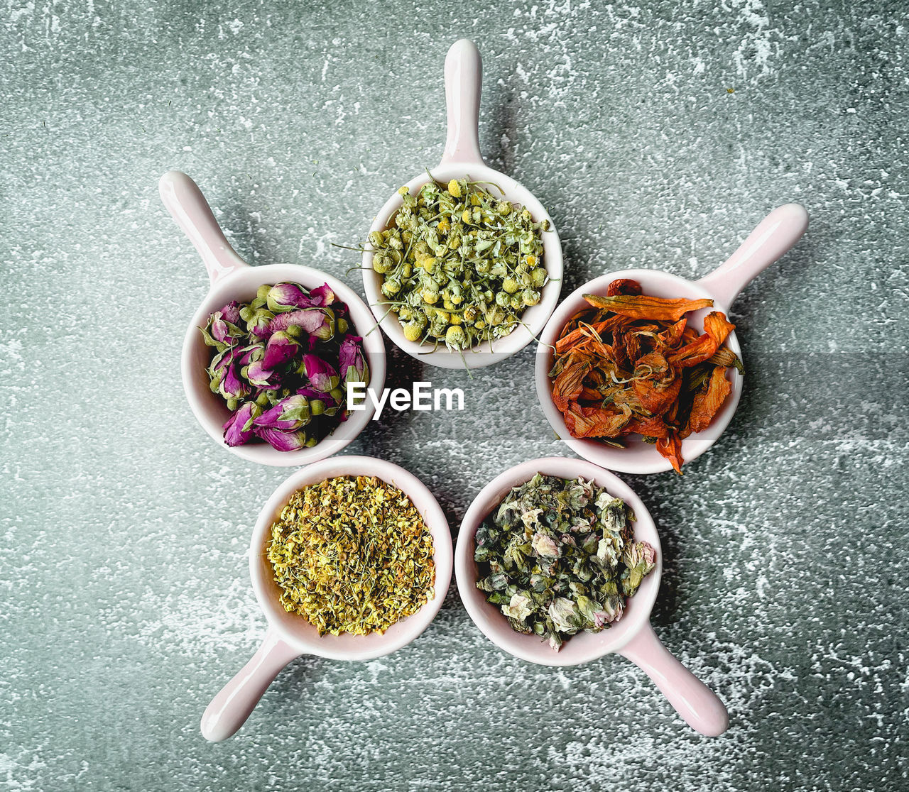 Directly above shot of dried flowers for making drinking te in bowl on grey background 