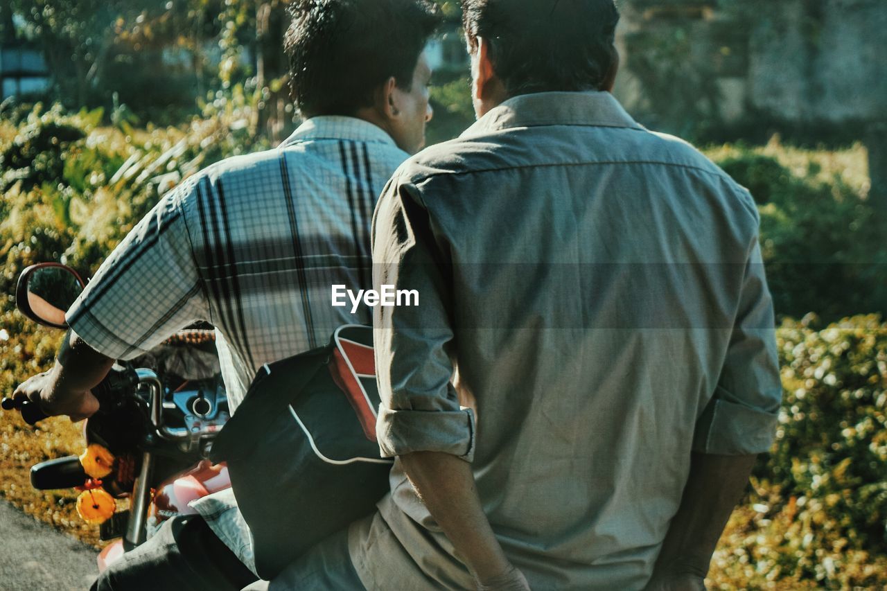 Rear view of man with friend riding motorcycle