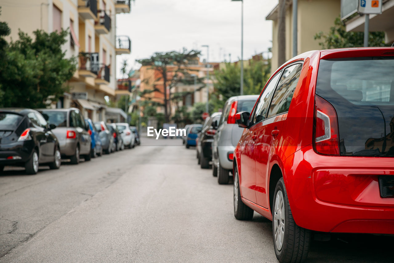 CARS PARKED ON ROAD ALONG BUILDINGS