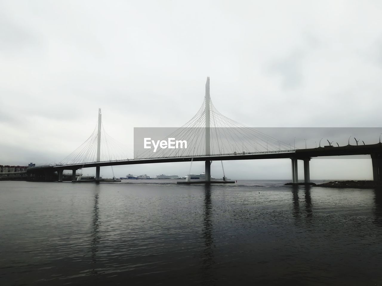 Bridge over calm river against sky