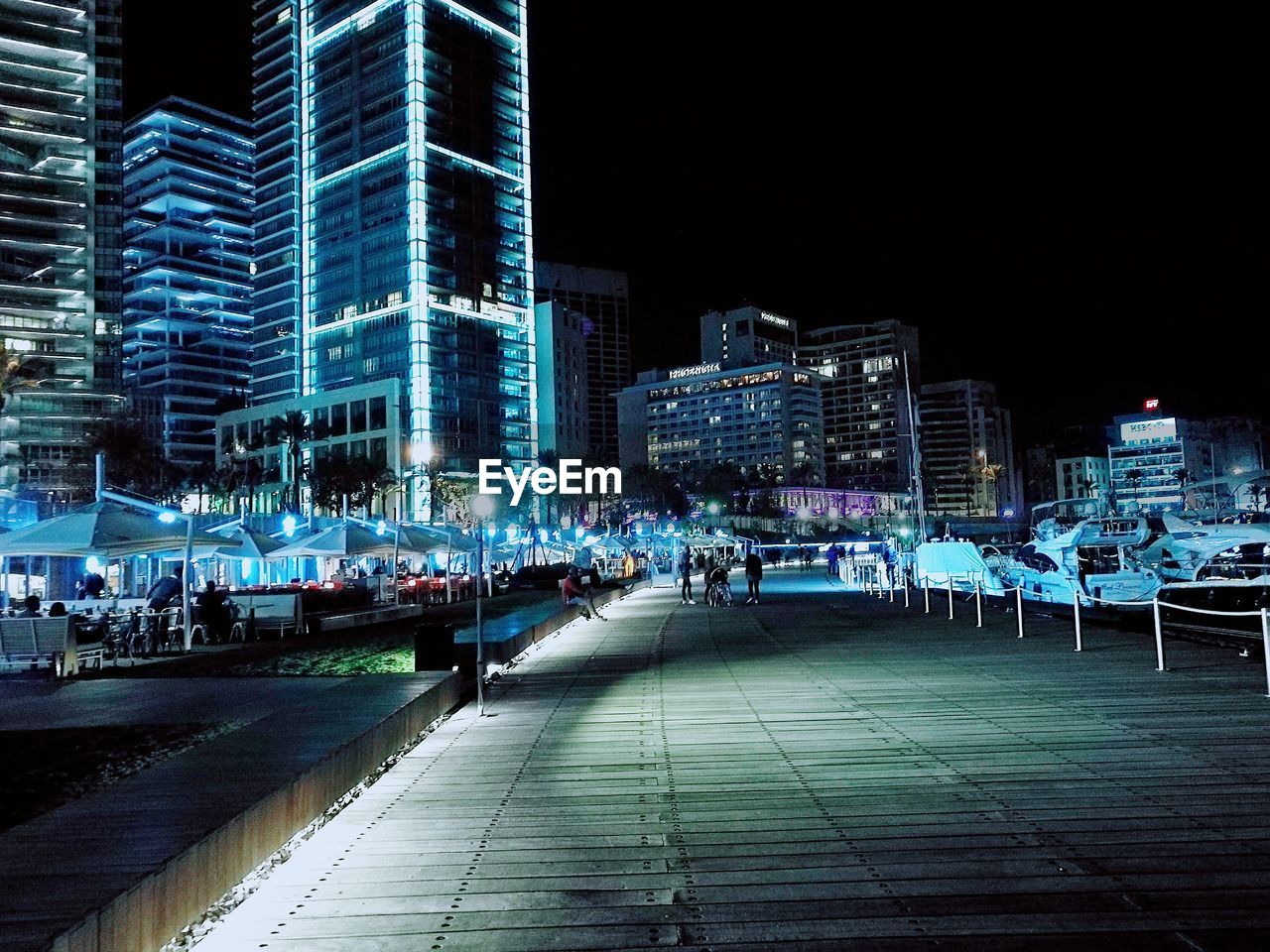 PEOPLE ON STREET AMIDST BUILDINGS IN CITY AT NIGHT