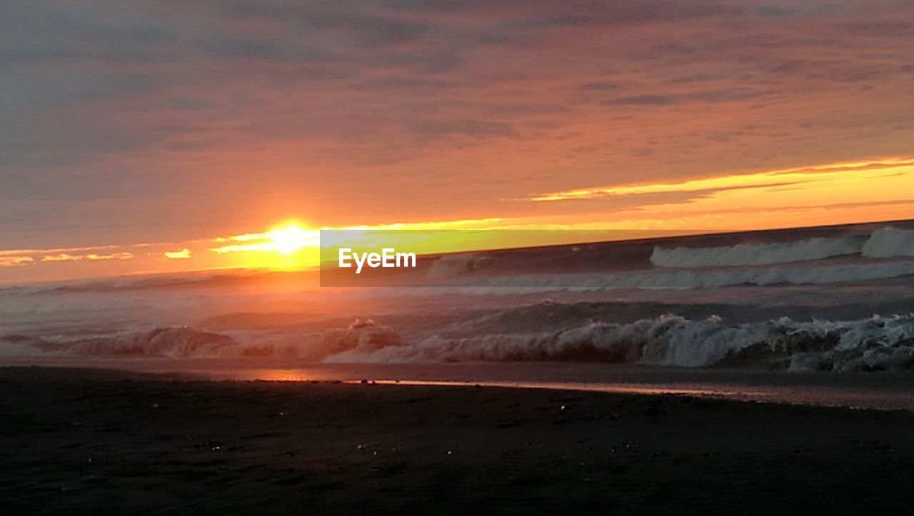 SCENIC VIEW OF BEACH AGAINST SKY AT SUNSET