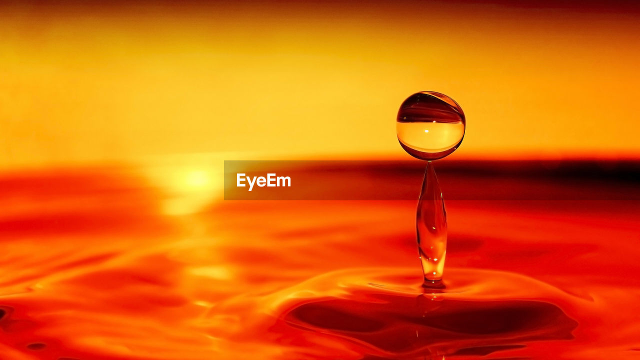 CLOSE-UP OF WATER DROP ON ORANGE SURFACE