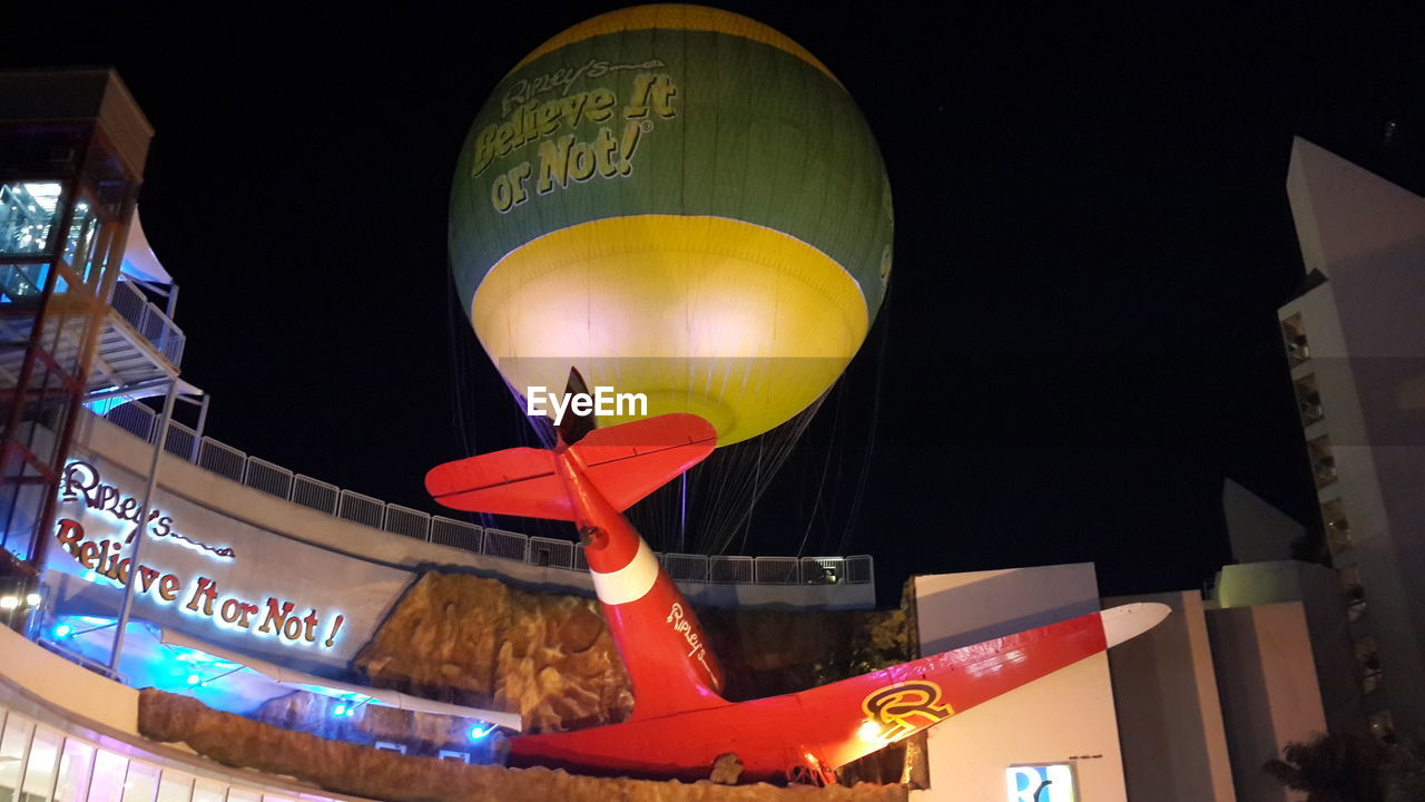 night, illuminated, architecture, text, hot air balloon, city, celebration, low angle view, building exterior, travel destinations, balloon, no people, event, lighting equipment, communication, tradition, transportation, built structure, outdoors, travel, traditional festival, holiday, nature