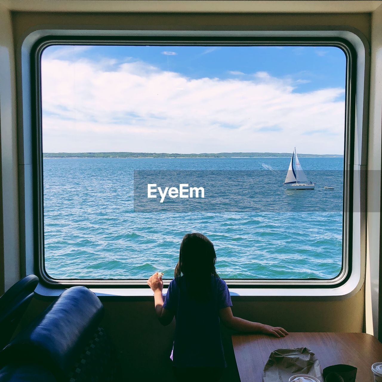 Rear view of girl looking at sea through window