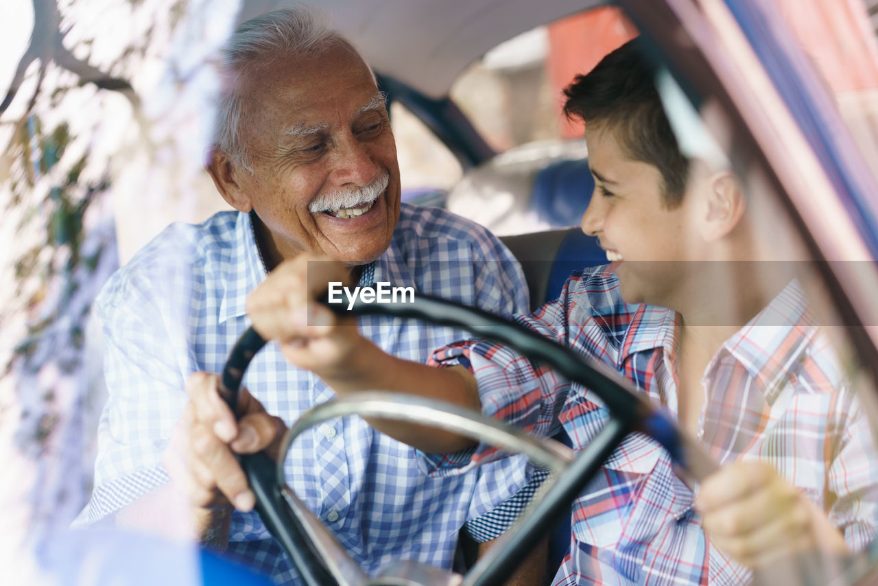 Senior man looking at grandson driving car