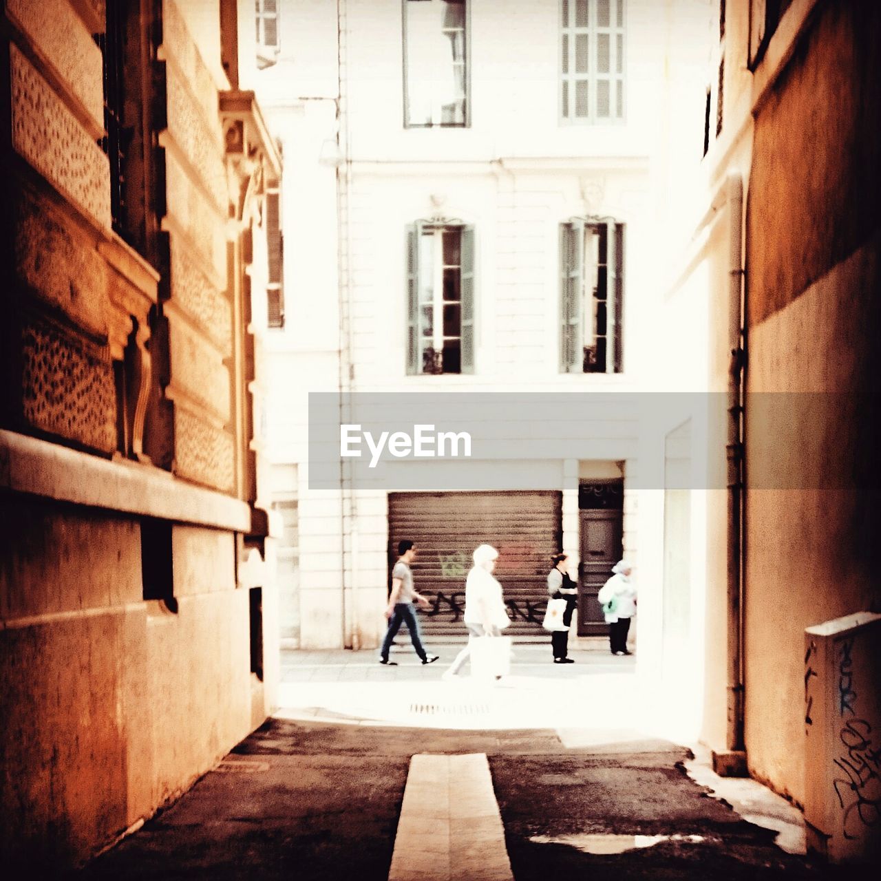 PEOPLE WALKING ON STREET AMIDST BUILDINGS IN CITY