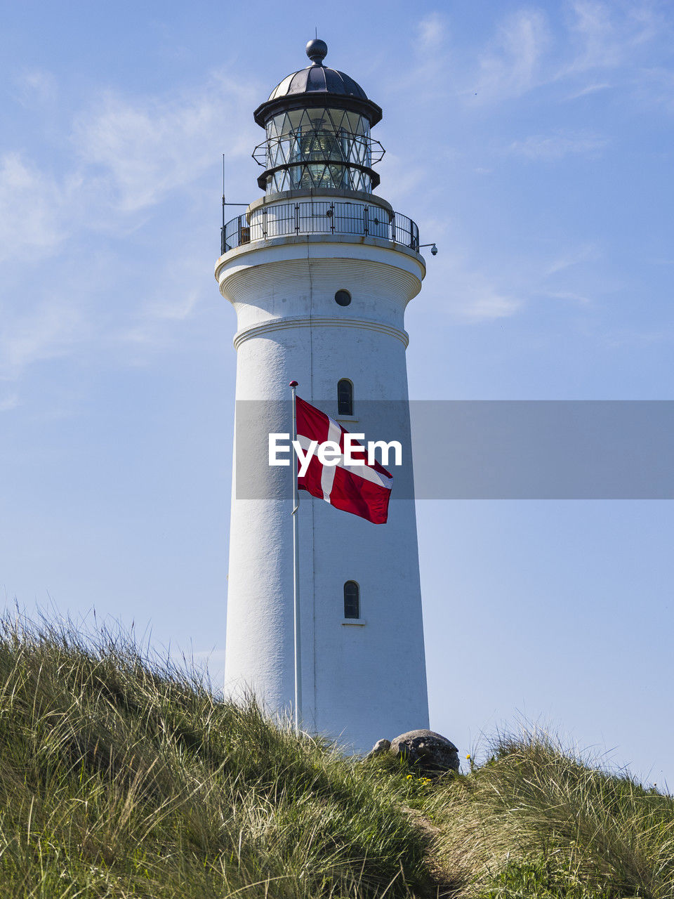 Low angle view of lighthouse with danish flag in foreground