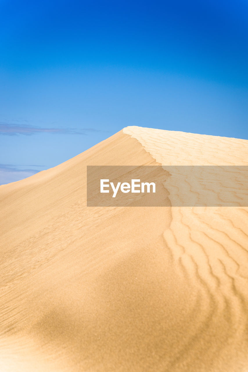 Sand dunes in desert against clear blue sky