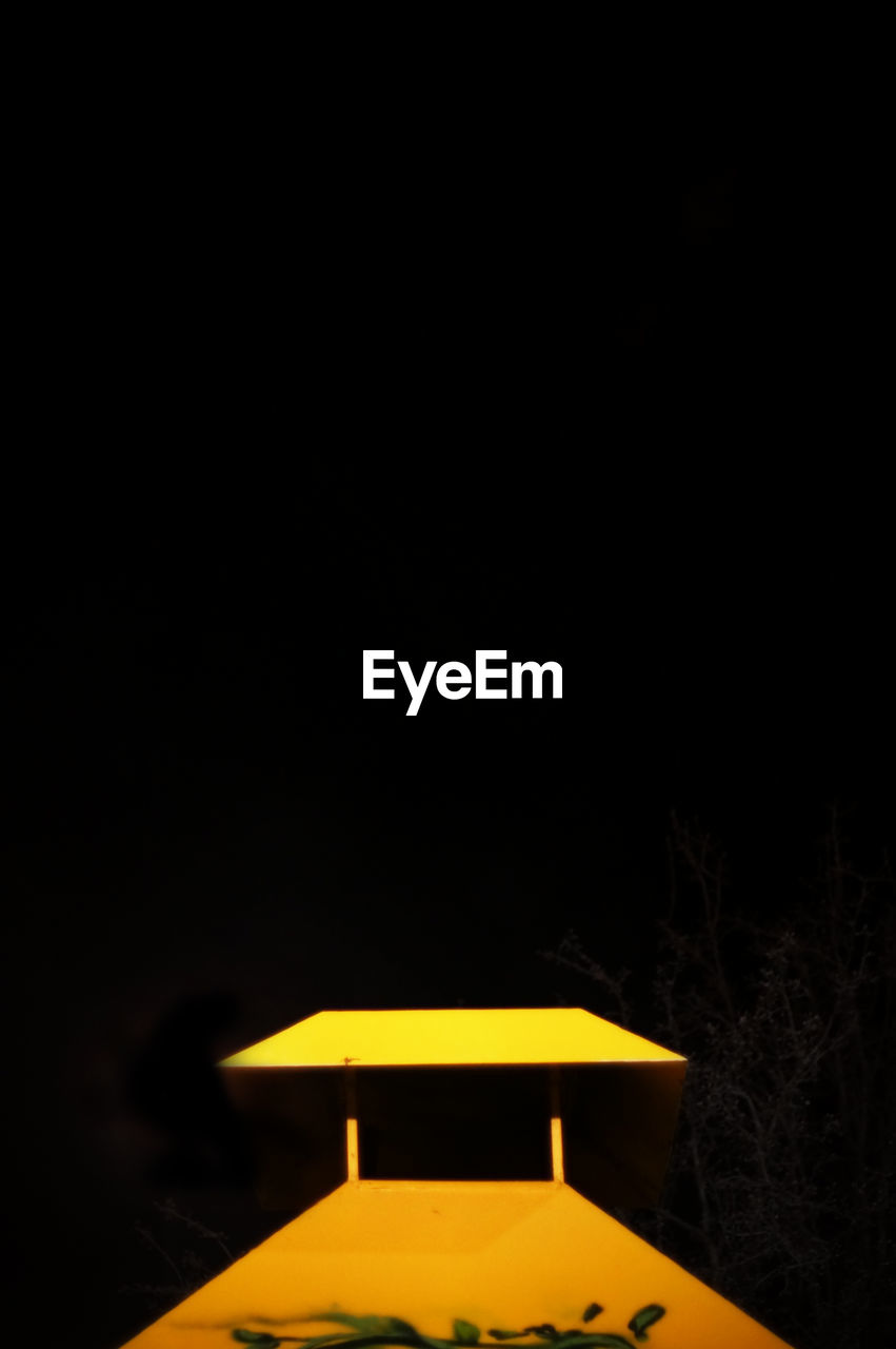 night, copy space, no people, lighting equipment, illuminated, yellow, outdoors, electricity, roof, built structure, architecture, clear sky, nature, black background, sky, close-up