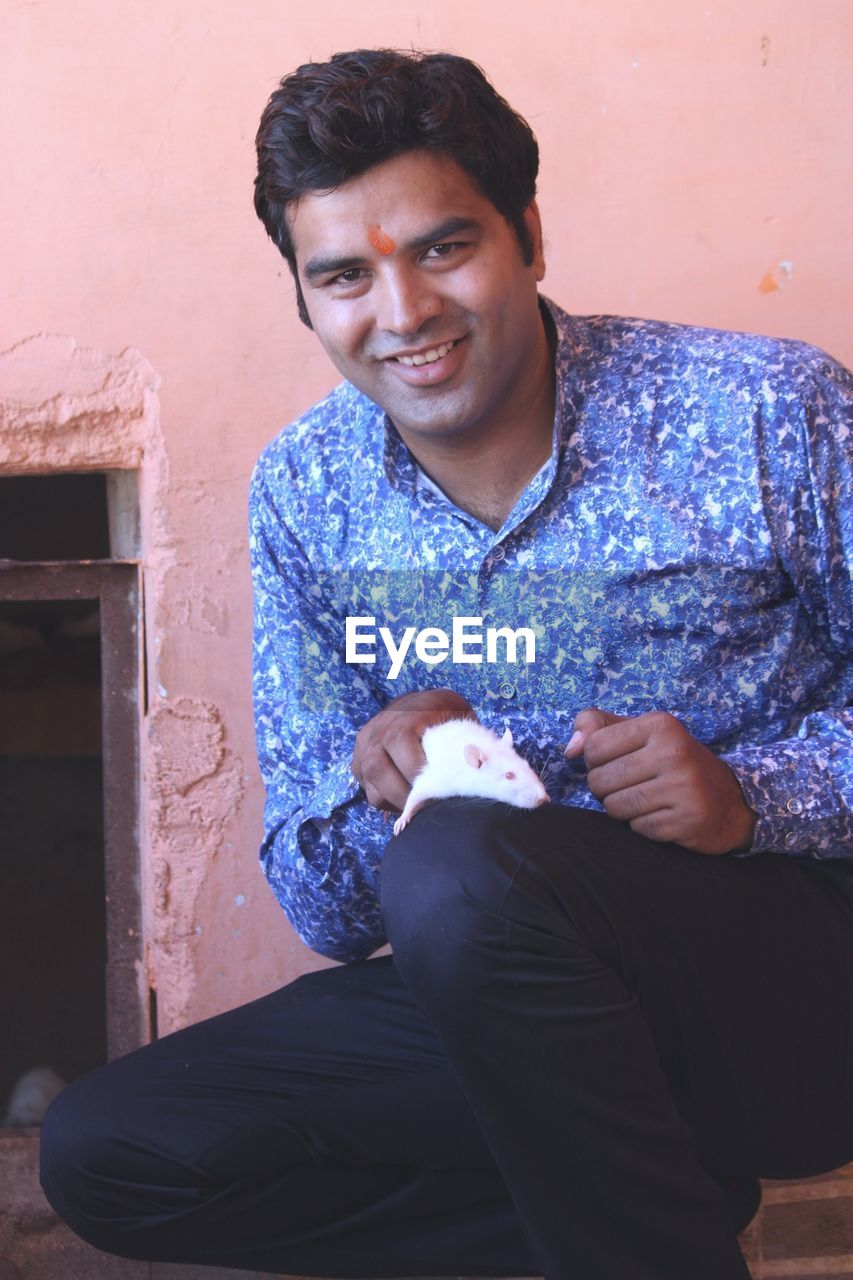 Portrait of smiling young man holding mouse