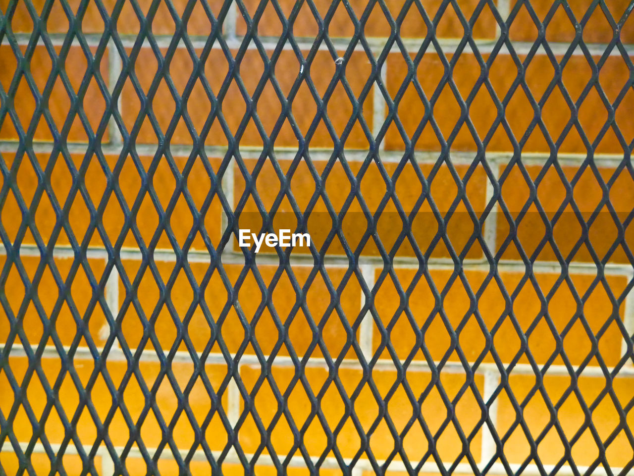 FULL FRAME SHOT OF CHAINLINK FENCE IN CITY SEEN THROUGH METAL GRATE