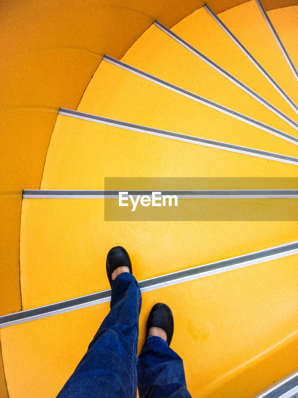 Low section of woman standing on spiral staircase