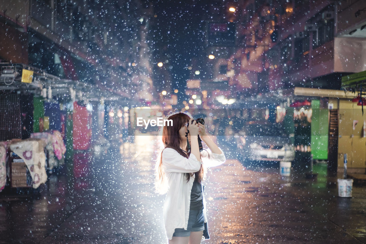 FULL LENGTH OF WOMAN STANDING ON WET STREET