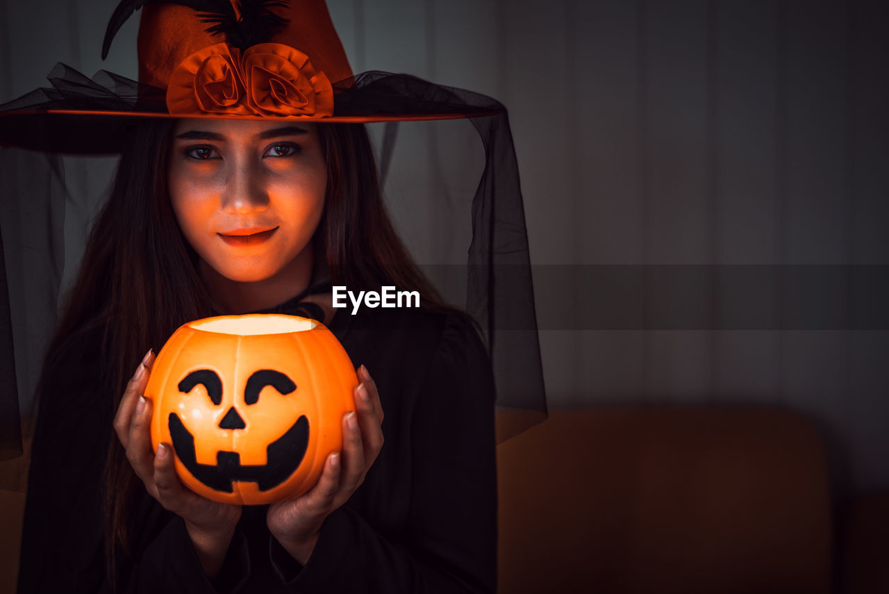 PORTRAIT OF WOMAN WITH ORANGE PUMPKIN IN HALLOWEEN