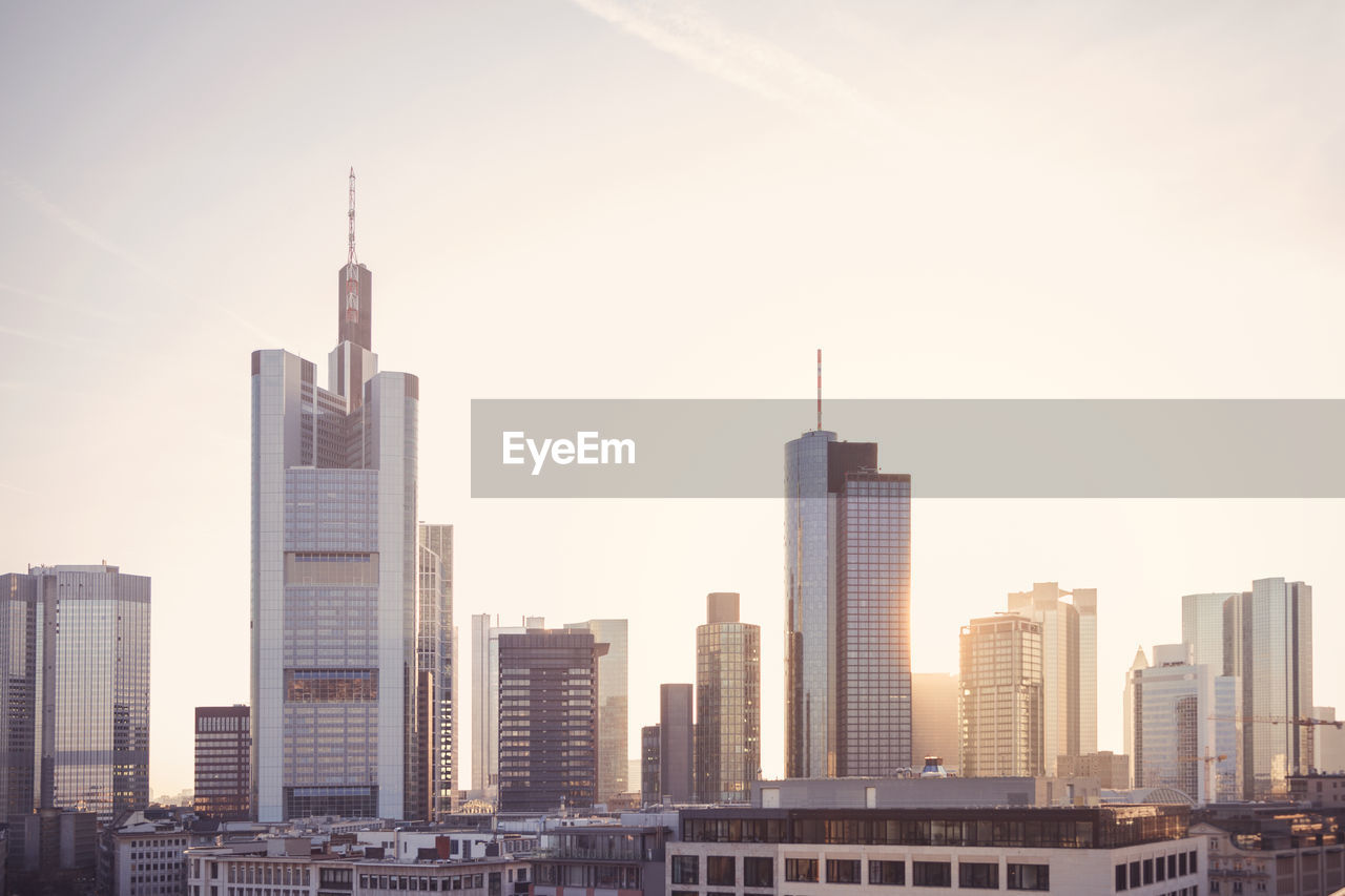 Modern buildings against sky in city during sunset