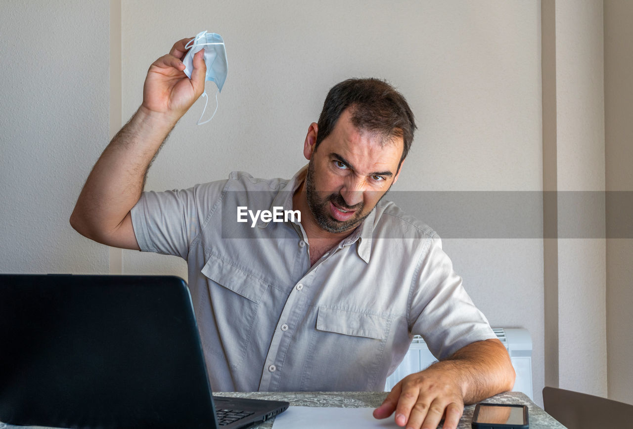 Frustrated man wearing flu mask sitting at office