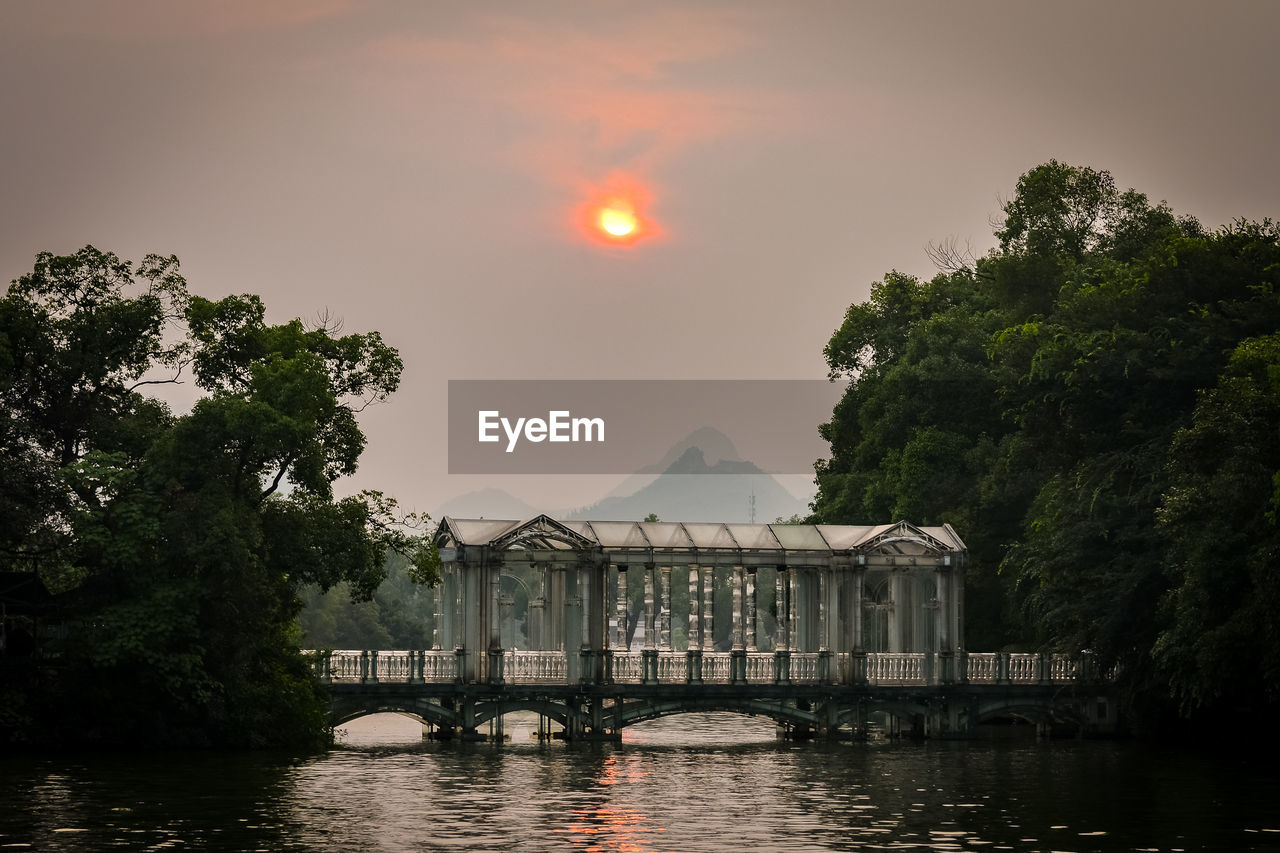 SCENIC VIEW OF RIVER BY TREES AGAINST SKY DURING SUNSET