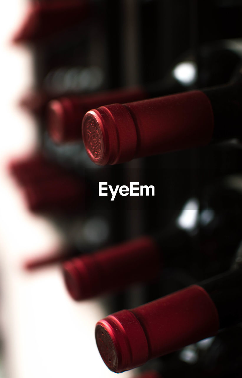 Close-up of red wine bottles on rack