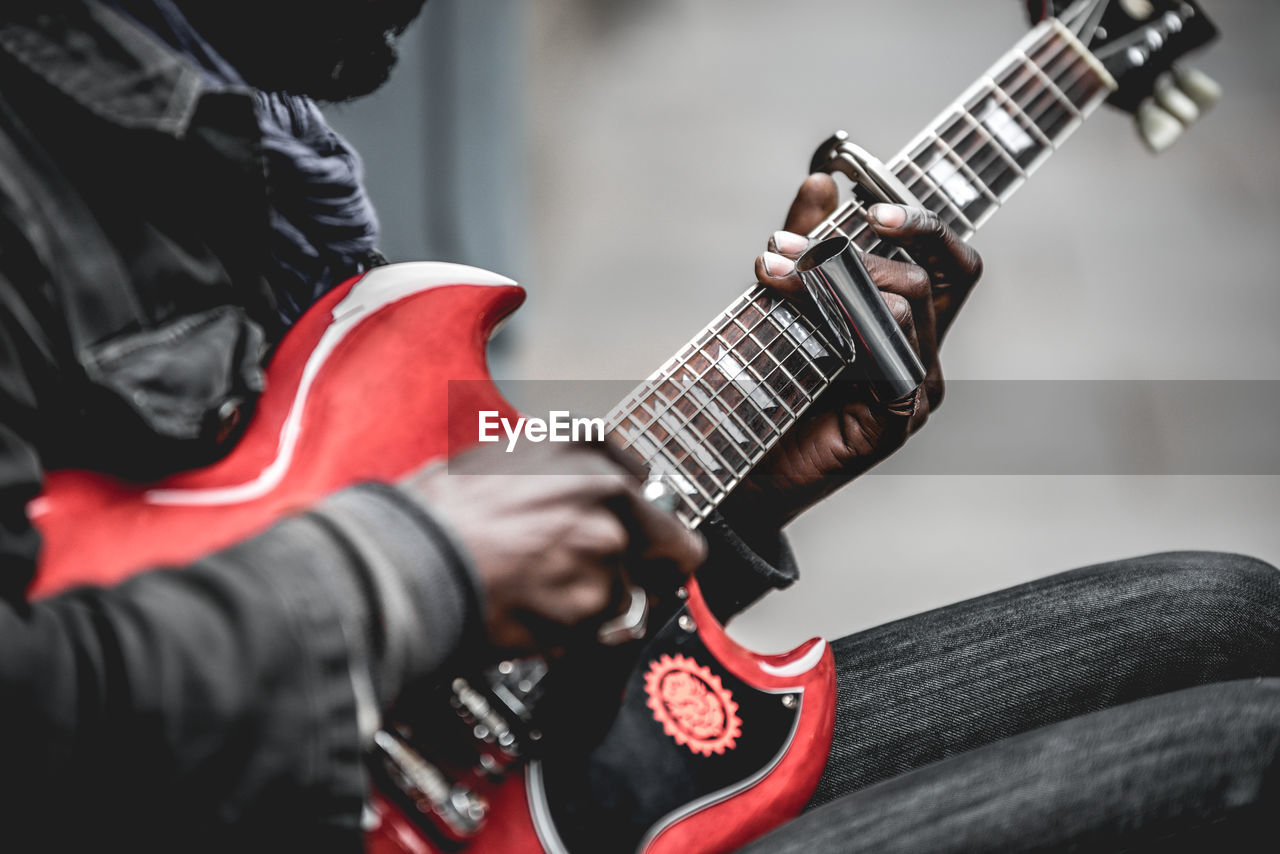 MIDSECTION OF MAN PLAYING GUITAR AT MUSIC CONCERT