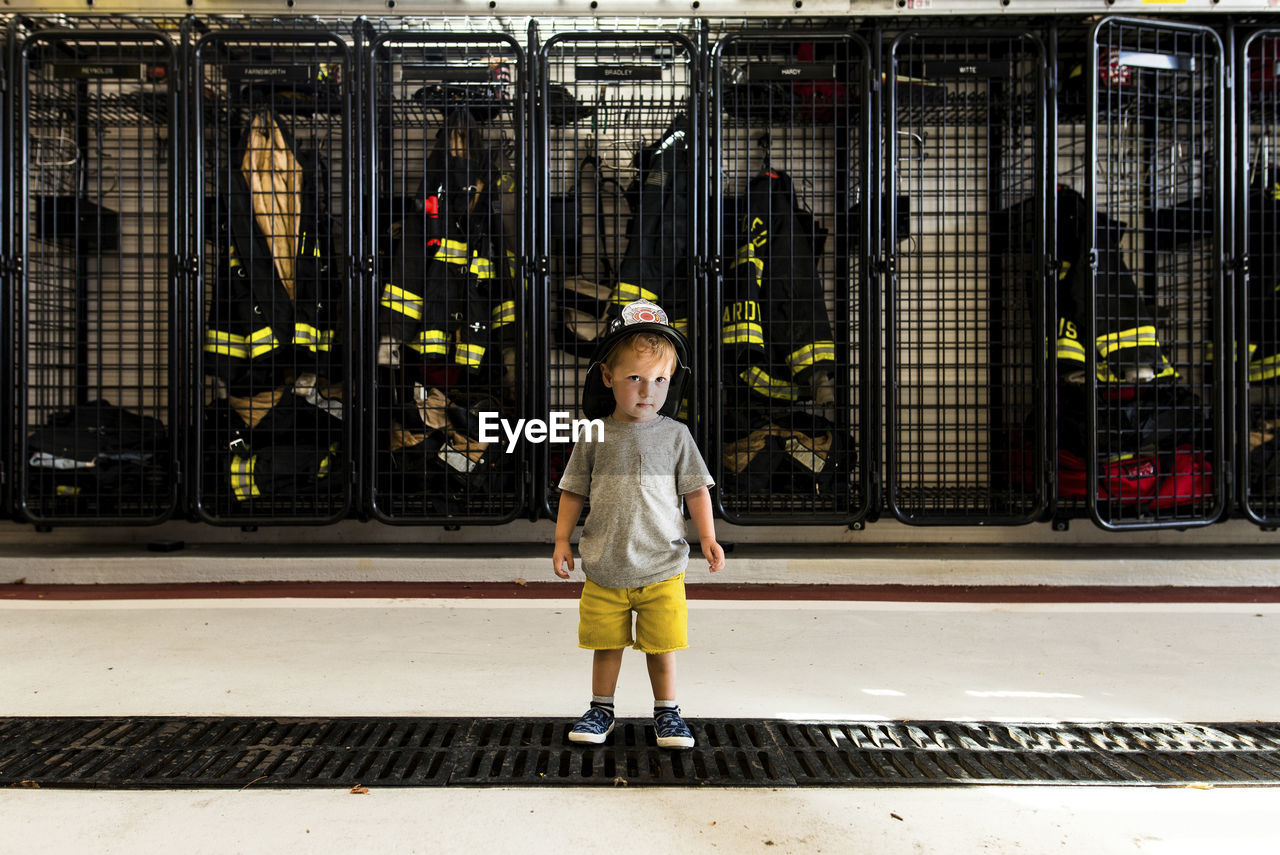 Full length of boy wearing firefighter's helmet while standing at fire station
