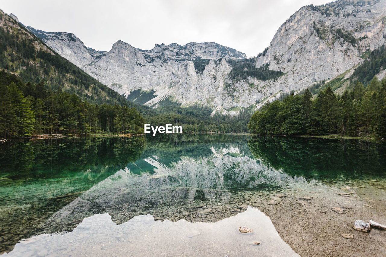 Rocky mountains and trees reflecting in lake