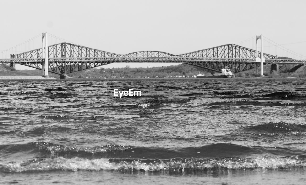 Suspension bridge over sea against clear sky