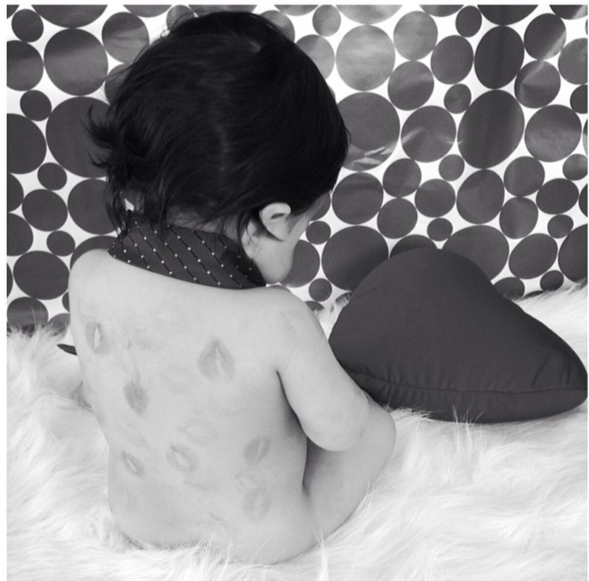 Rear view of baby sitting with heart shape pillow