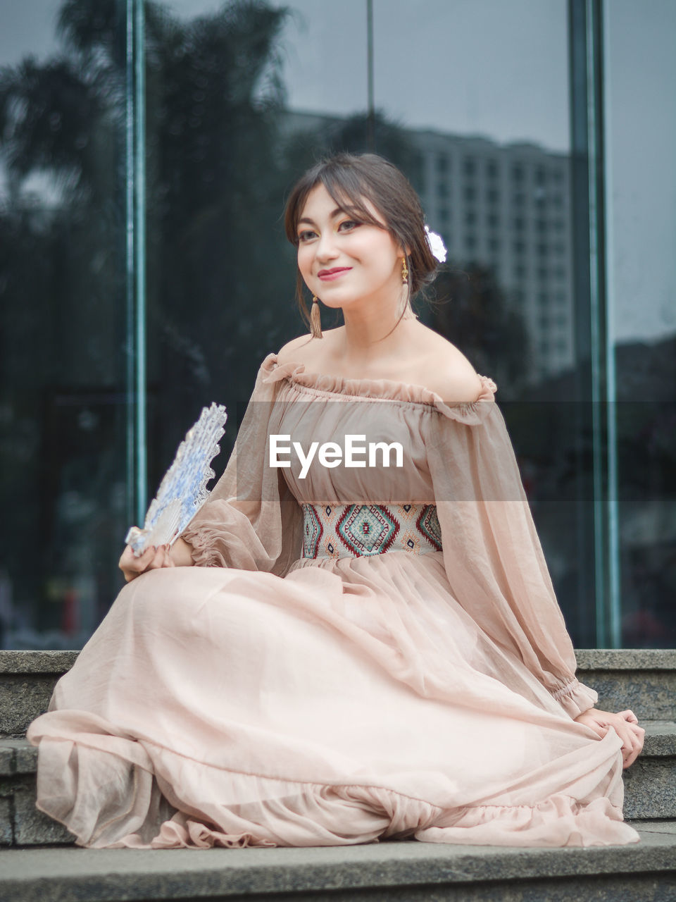 Beautiful woman in dress sitting against building