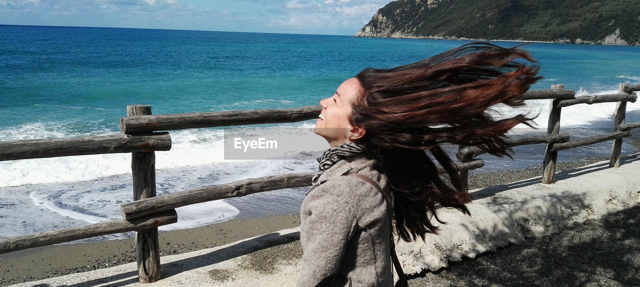 Smiling woman tossing hair at beach