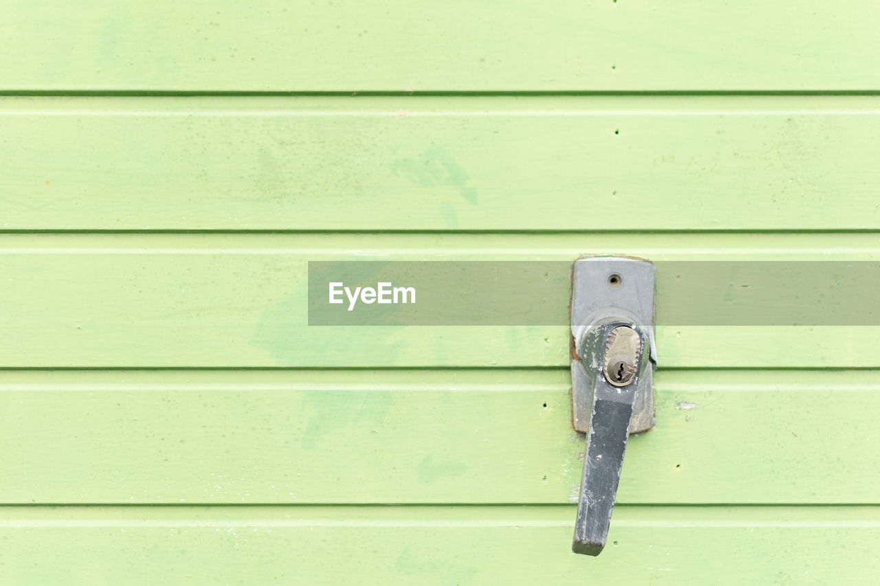 Metal door handle with keyhole on a green garage door.