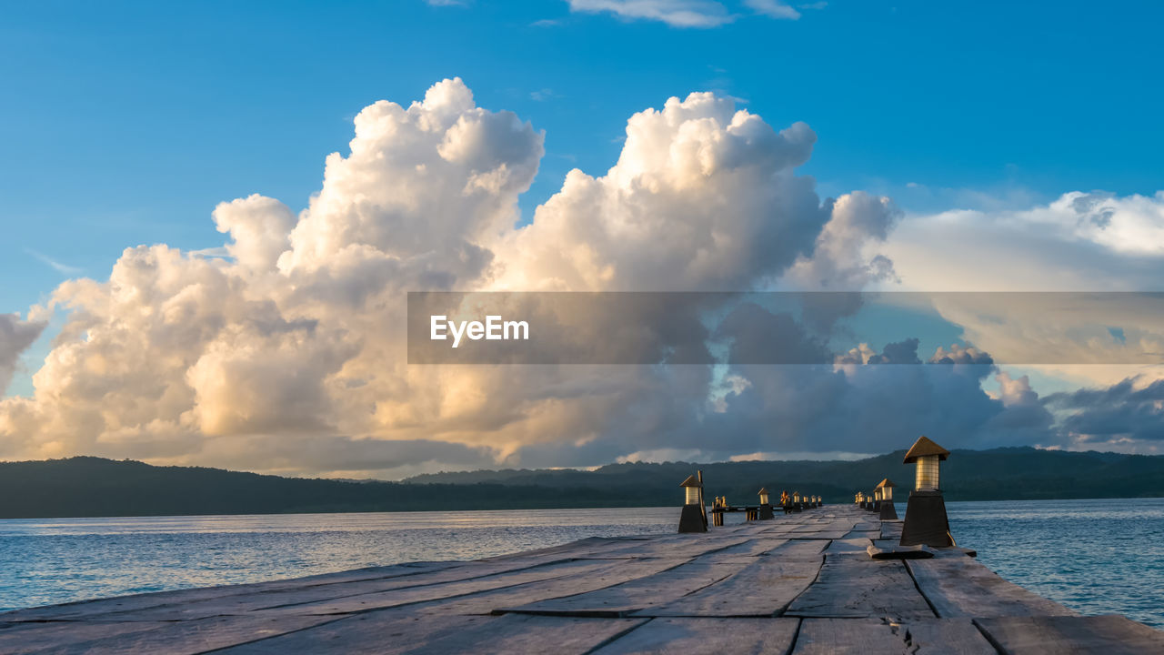 Empty jetty on lake against sky