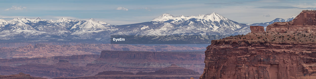 Panoramic view of rocky canyon with snow capped mountains in background