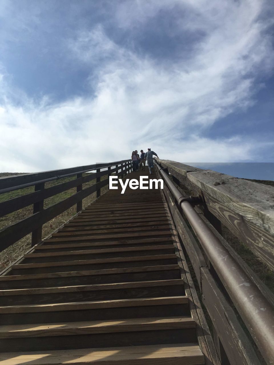 PEOPLE ON FOOTBRIDGE BY BRIDGE AGAINST SKY