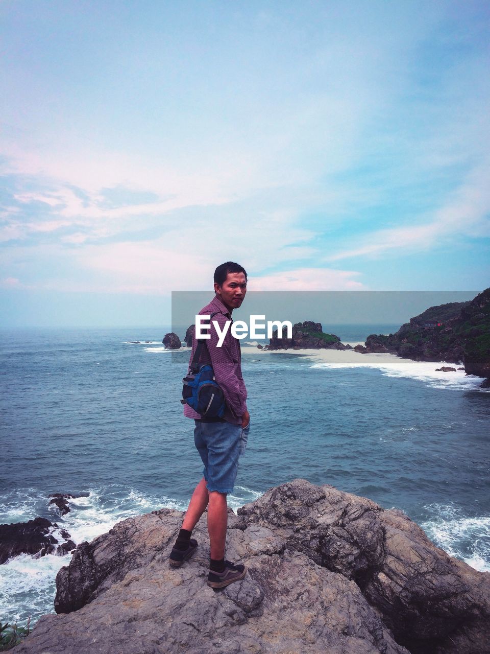 FULL LENGTH OF MAN STANDING ON ROCK AGAINST SEA