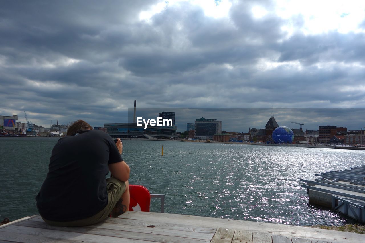 REAR VIEW OF WOMAN SITTING ON PROMENADE