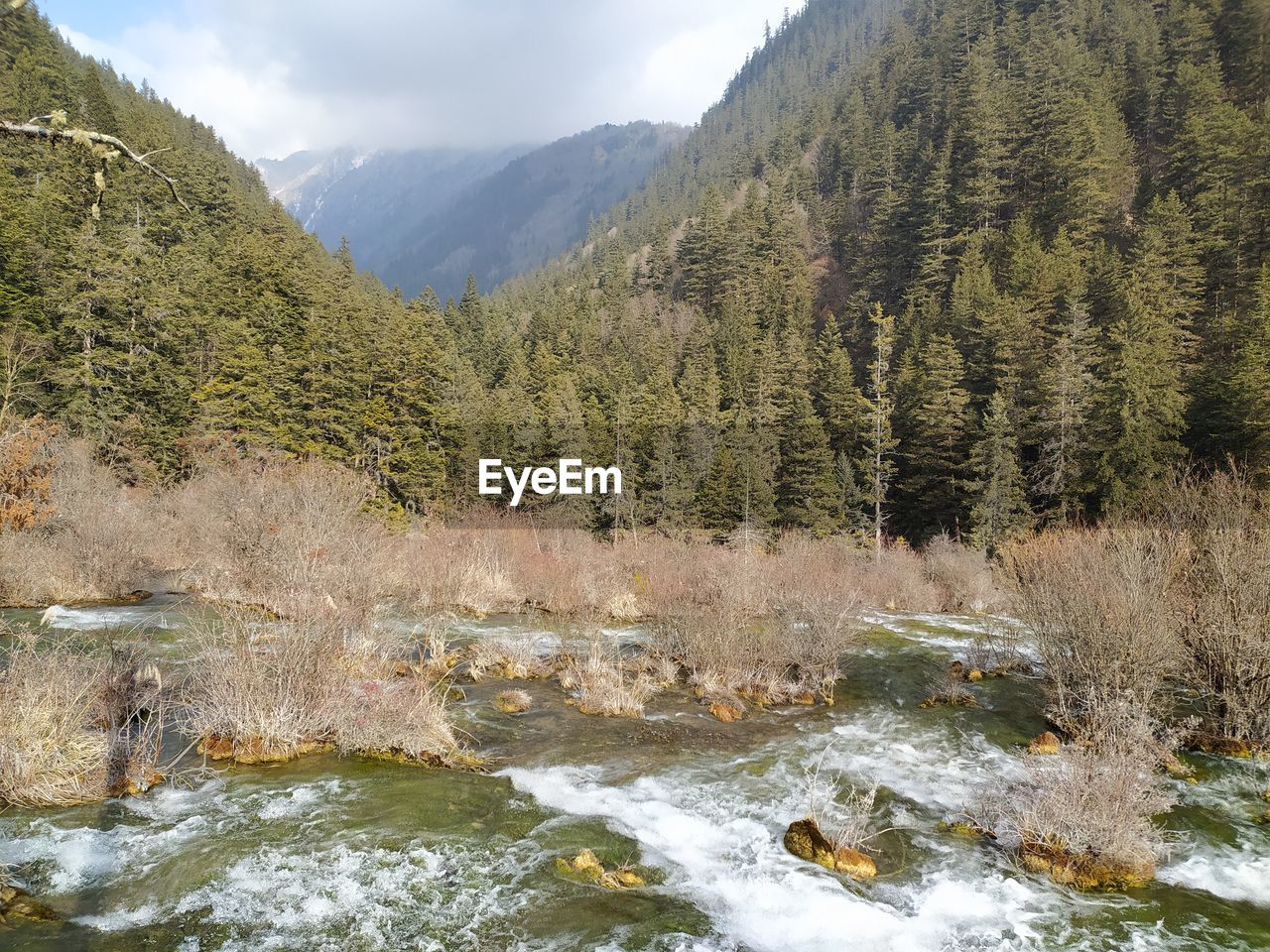 Scenic view of river by mountains against sky