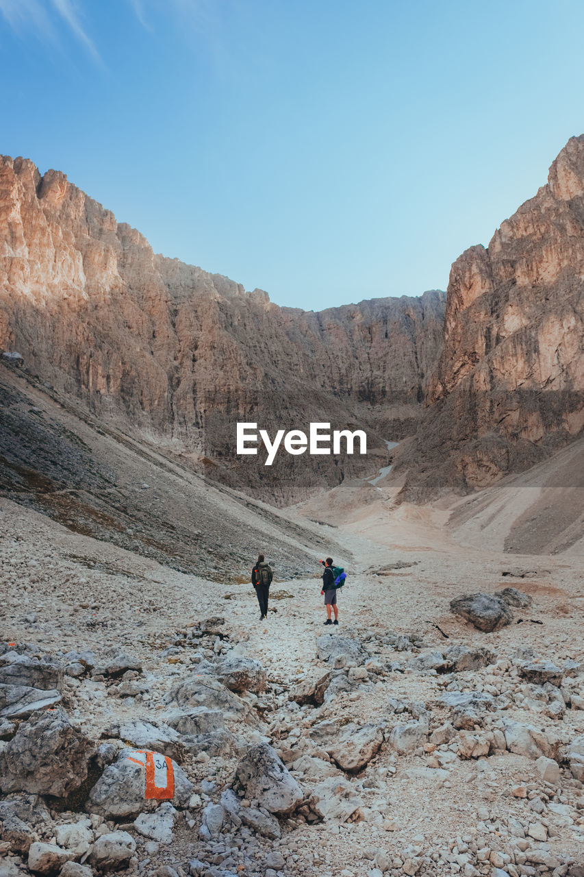 Rear view of man walking hiking on mountain during daytime