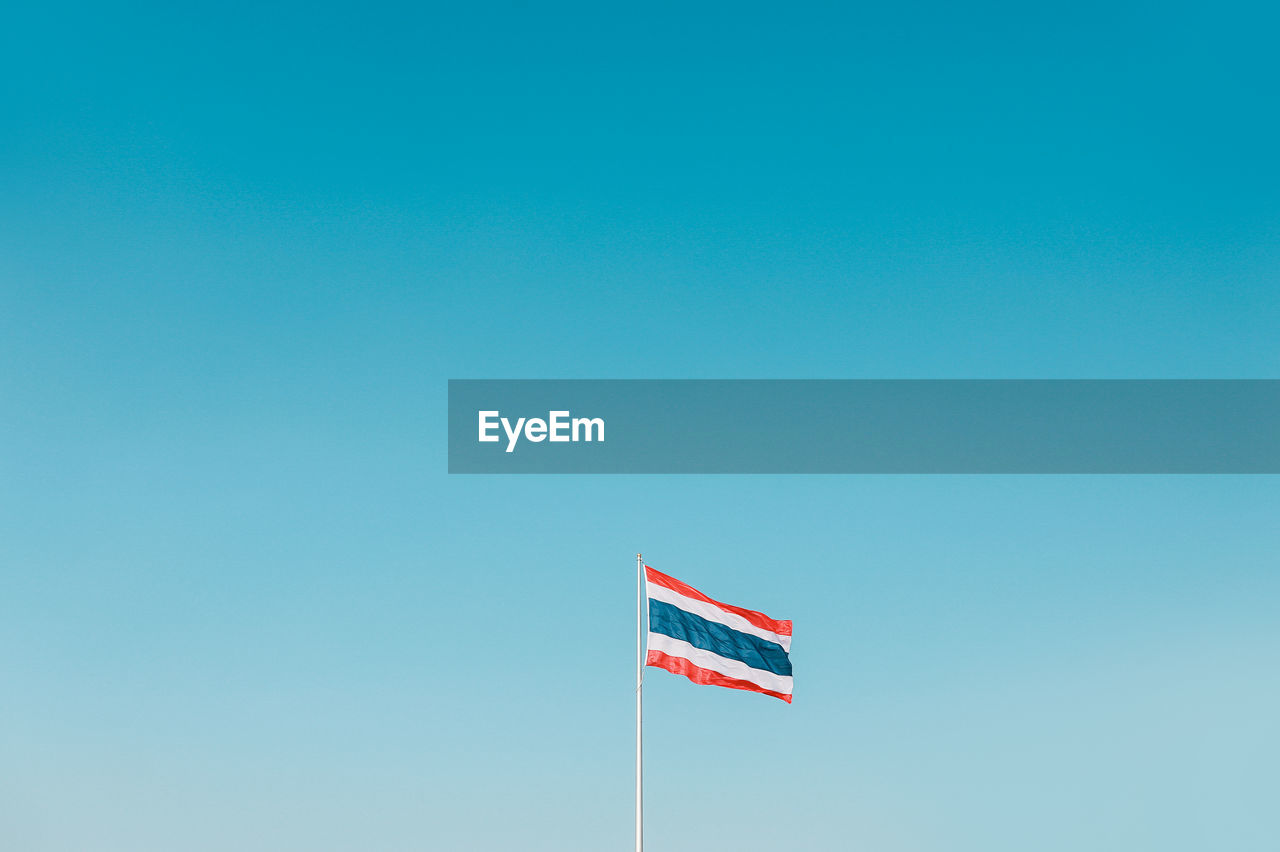 Low angle view of thai flag against clear blue sky