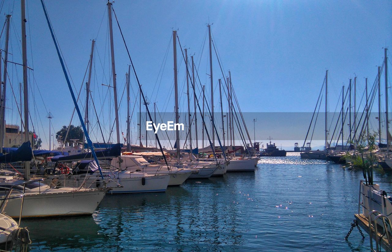 Sailboats moored at harbor against sky