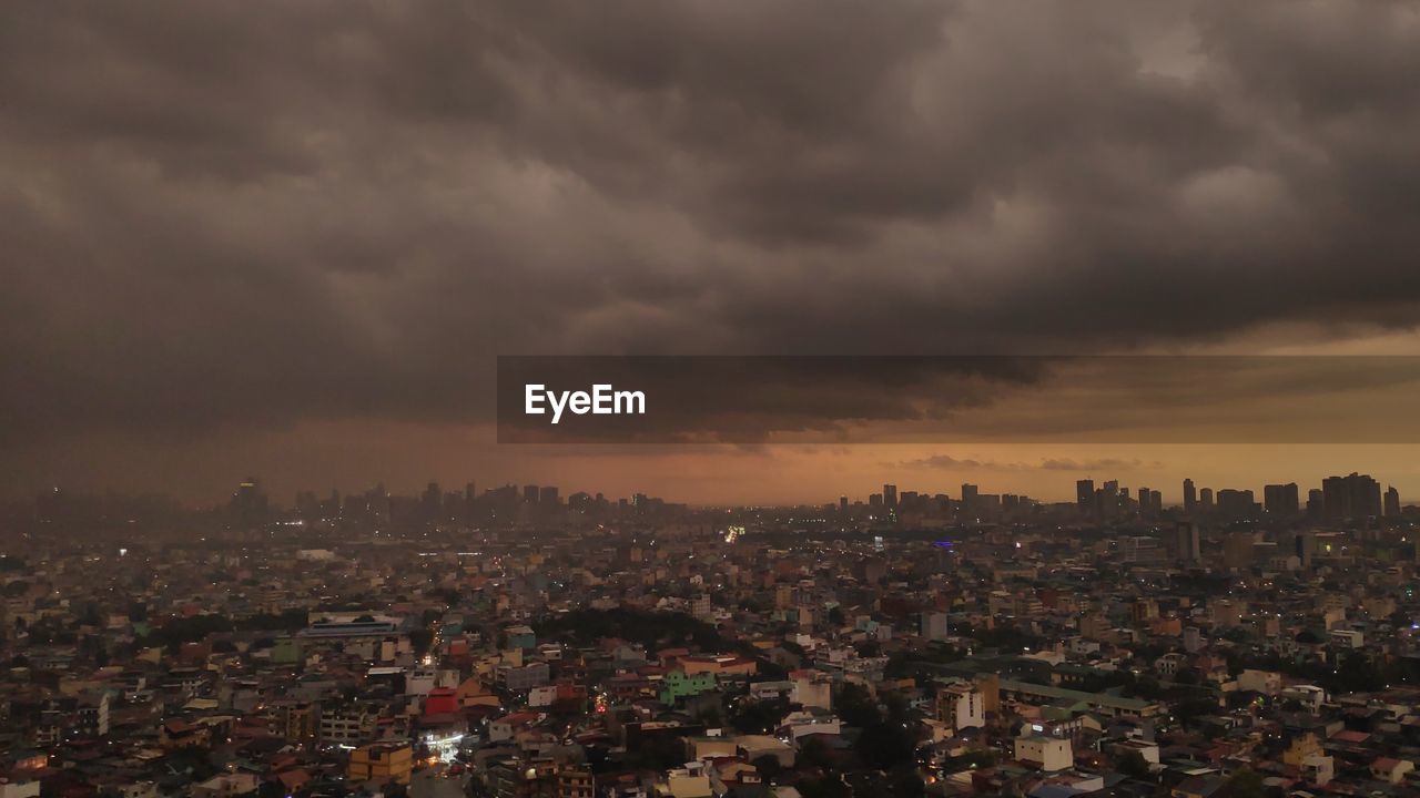 Aerial view of city against cloudy sky at dusk