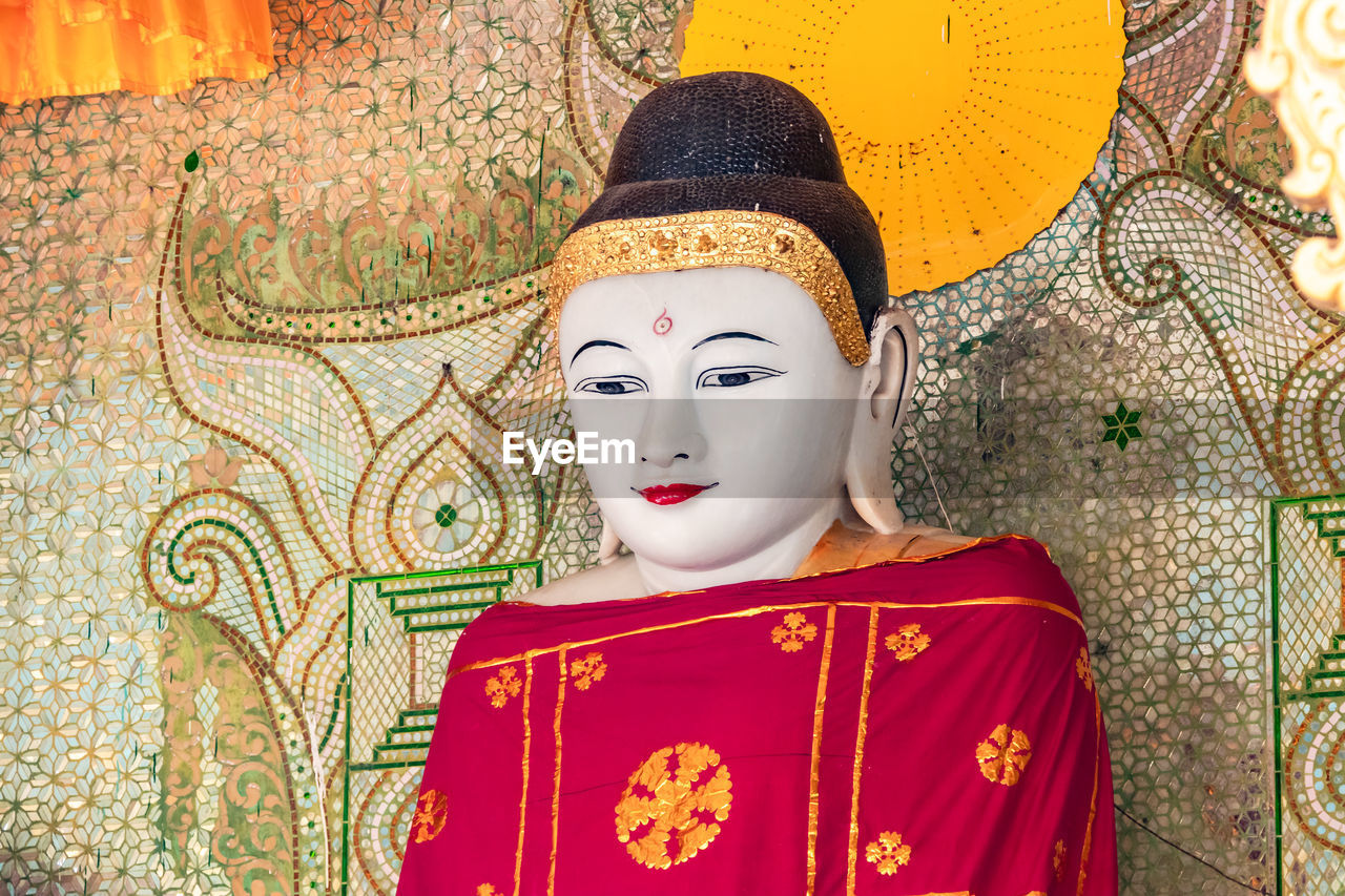 Close-up of a buddha statue with a red robe  inside the shwedagon pagoda in yagon, myanmar