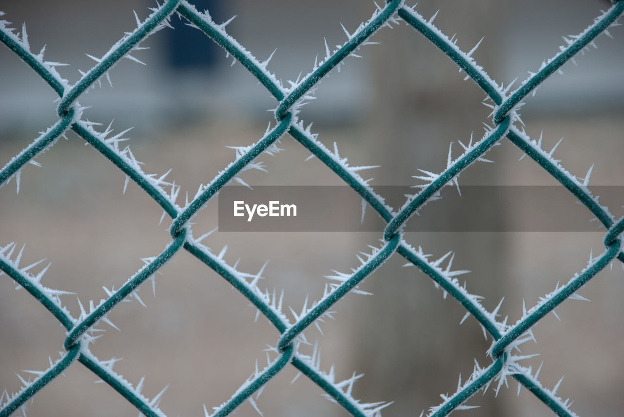 CLOSE-UP OF CHAINLINK FENCE AGAINST BLUE SKY