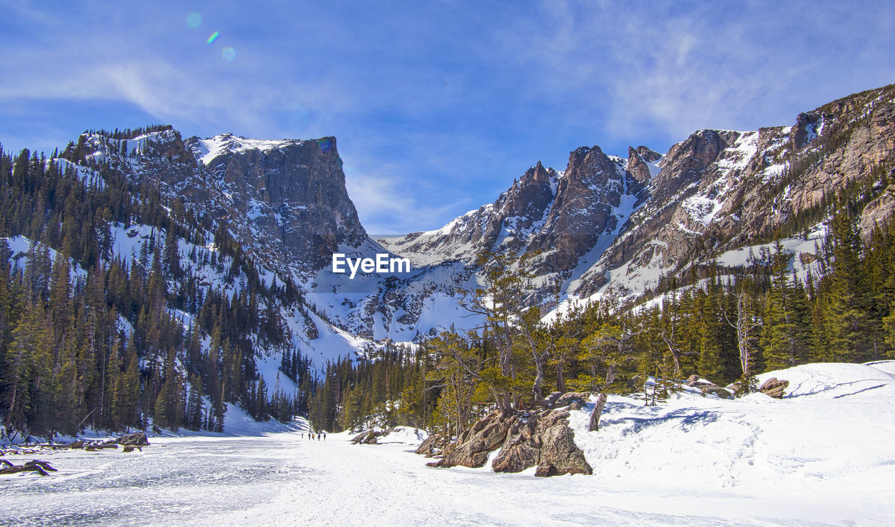 Scenic view of snow covered field by mountains against sky