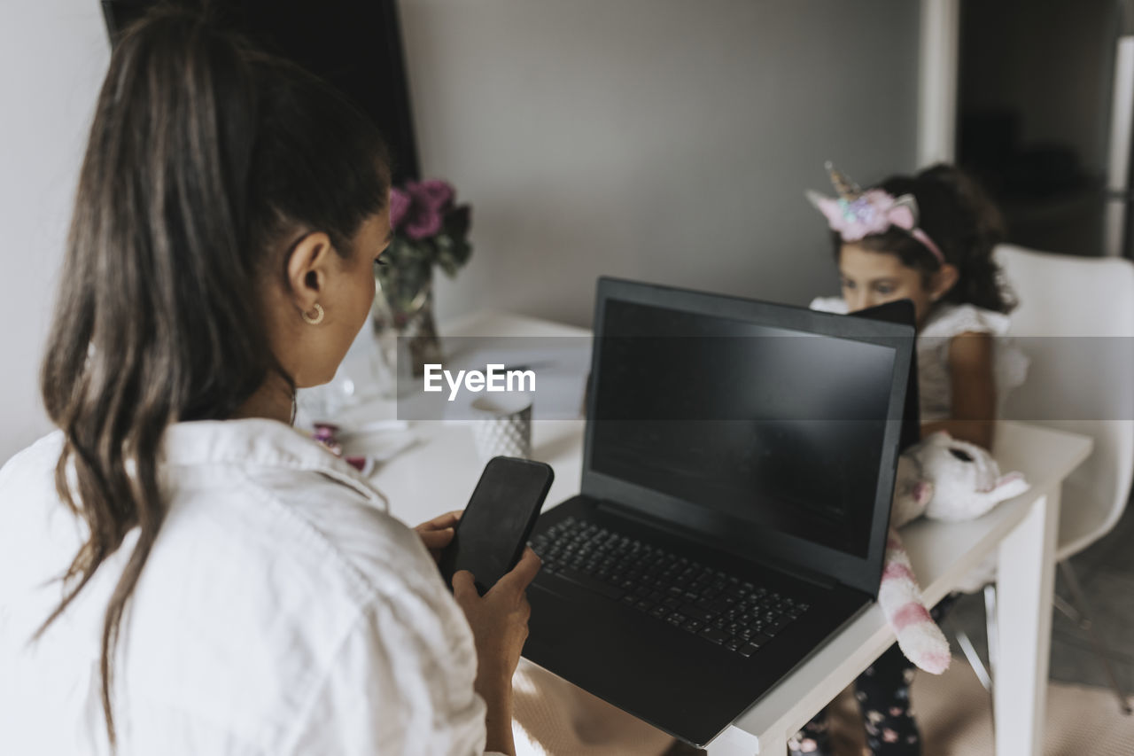 Woman working from home, girl on background