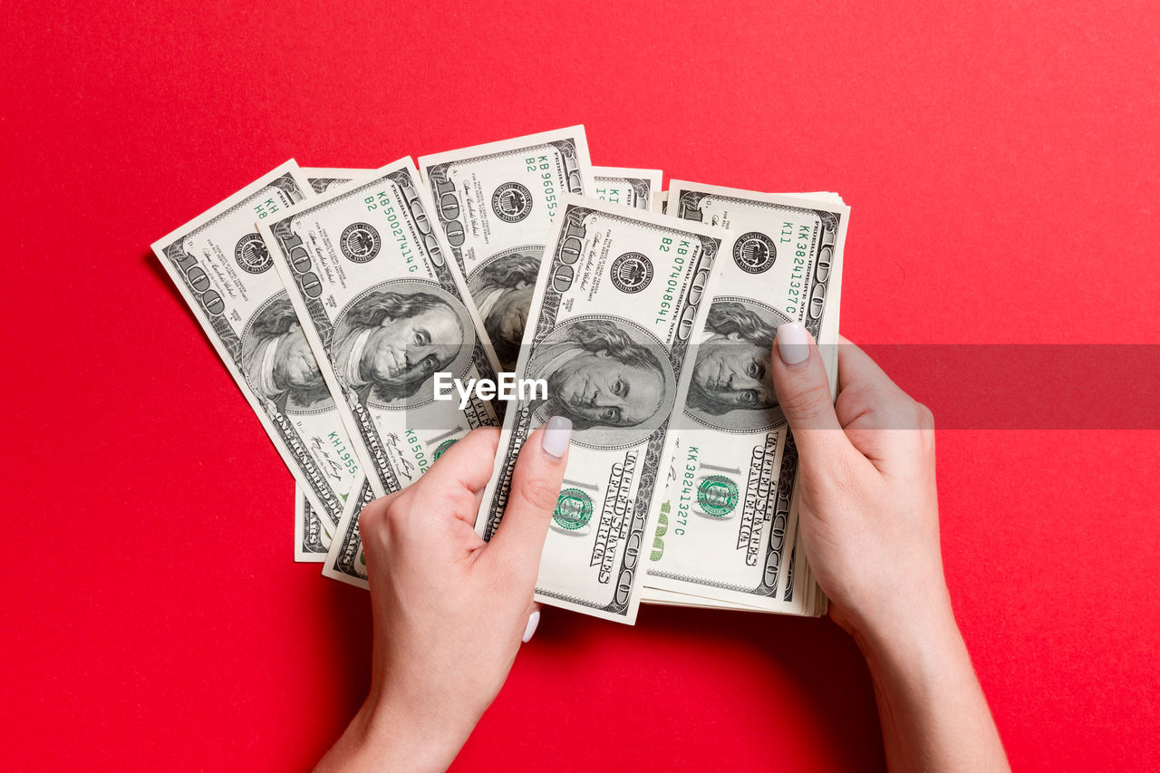 Close-up of hands with paper currency against red background