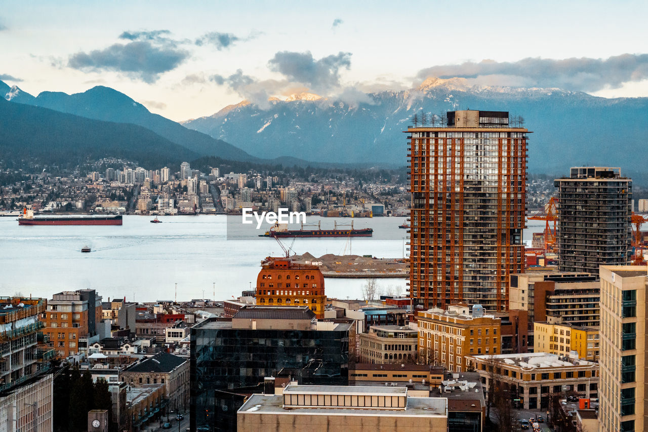 A city skyscraper view of north vancouver, gastown, mountains, water, and a soft pastel sunset