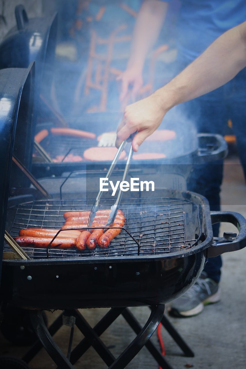 People preparing sausages on barbecue